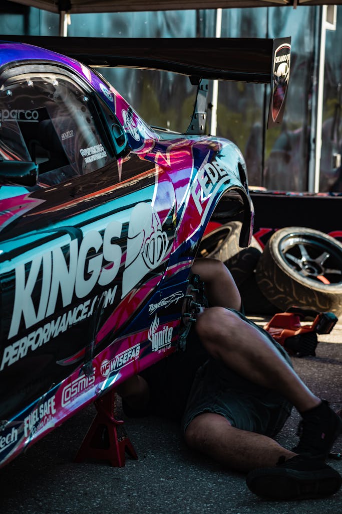 A mechanic repairs a colorful drift car, showcasing dynamic design and performance.