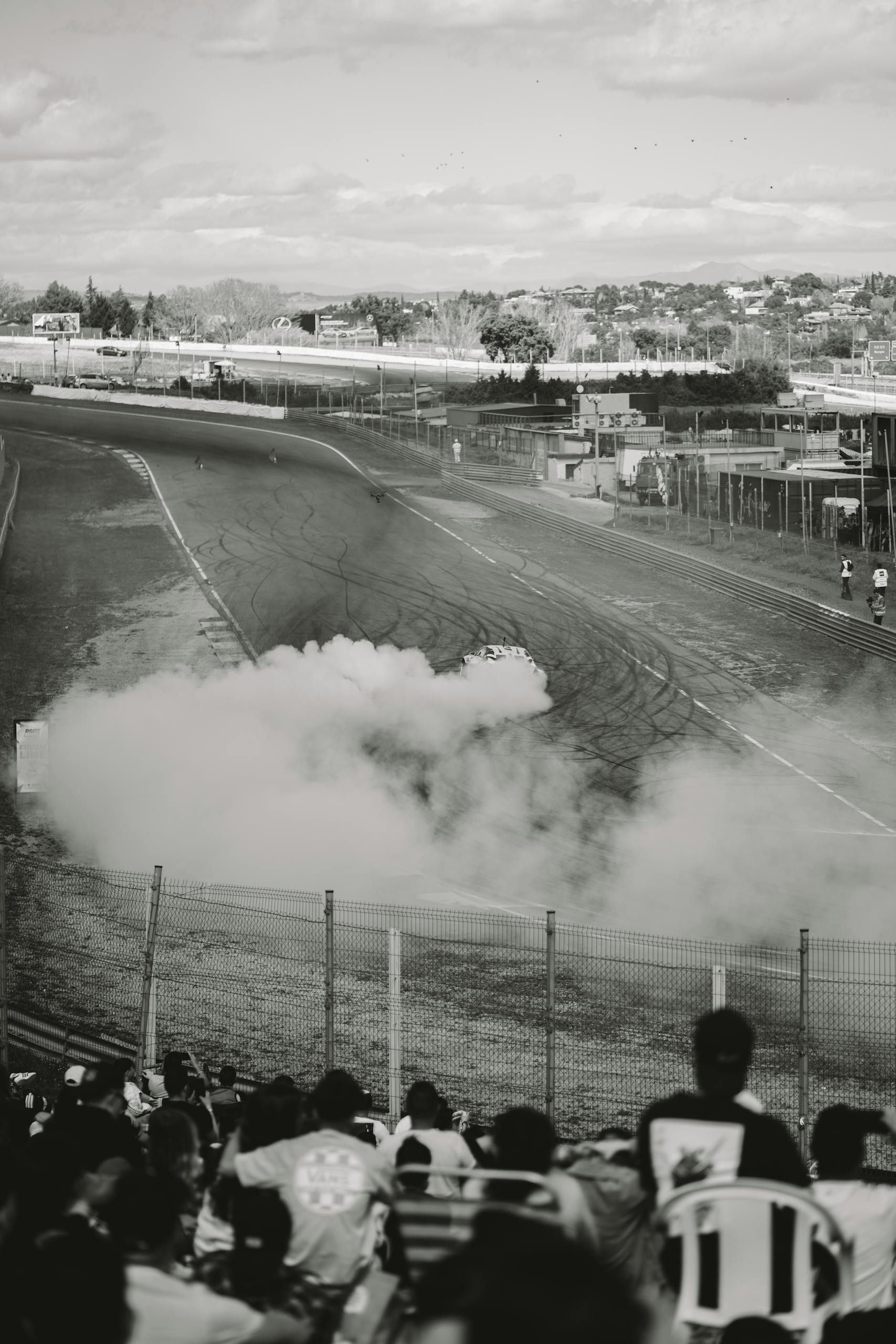 Black and white photo capturing a thrilling car drifting event at a racetrack in Madrid.